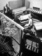 Harry Partch sits in a room dwarfed by big instruments all around him.