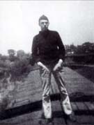 Harry Partch standing on top of a rail car with cap and turtle neck on.